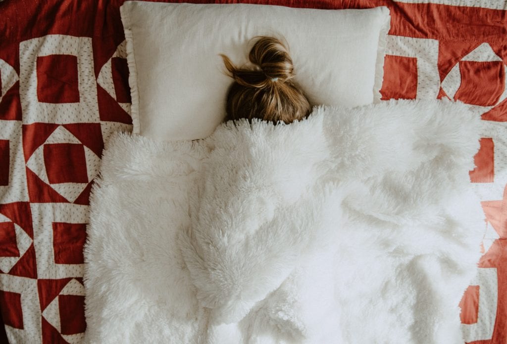 Woman Sleeping In Bed Covered In Blanket
