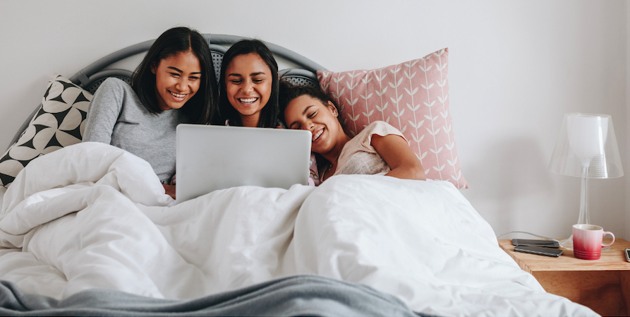 Three Sisters Watch A Movie On A Laptop In Bed 